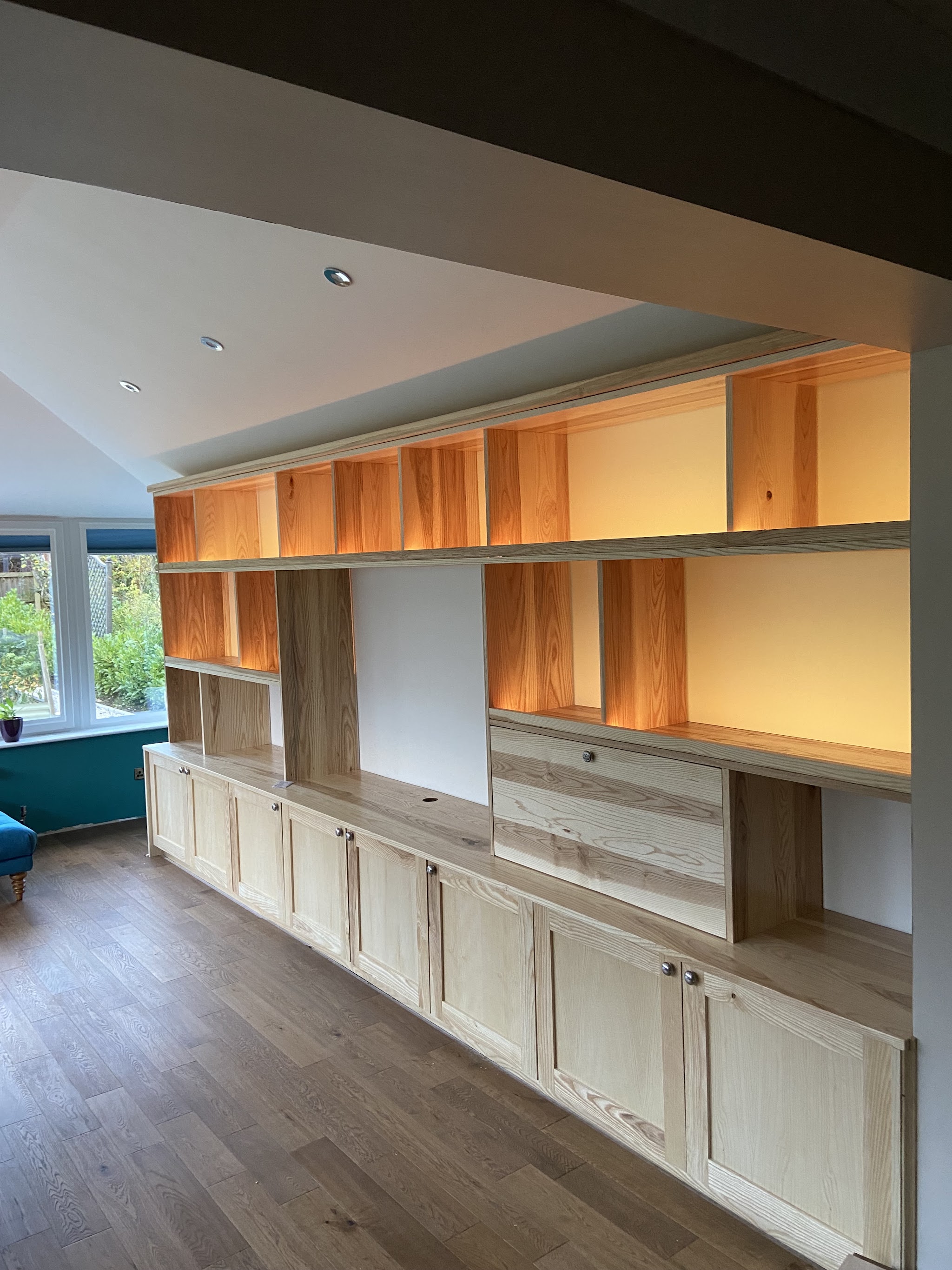Built-in timber shelving with warm LED lighting in every bay
